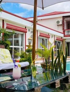 a patio with a glass table with a drink on it at Petite Flower Guest House in Talata-maty