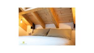 a bedroom with a white bed with wooden ceilings at La casa tra gli ulivi in Genova