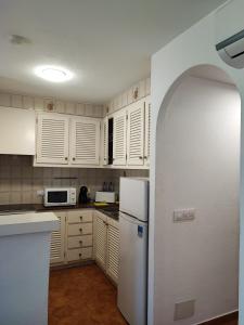 a kitchen with white cabinets and a white refrigerator at Apartamento colibrí in Alaior +8 photos