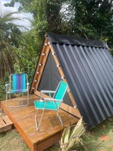 een tent en twee stoelen op een houten terras bij Smart camping Caçandoca in Ubatuba