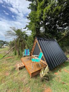 een hut met twee stoelen en een zwart dak bij Smart camping Caçandoca in Ubatuba