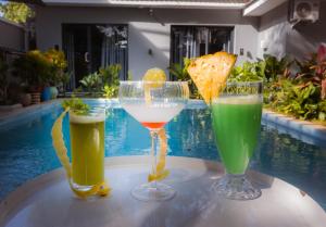 3 boissons assises sur une table à côté d'une piscine dans l'établissement The L Boutique Tz, à Dar es Salaam