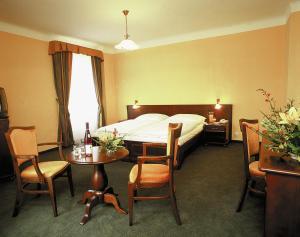 um quarto de hotel com uma cama, uma mesa e cadeiras em Hotel Certovka em Praga