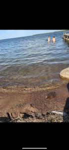 two people swimming in the water near the shore at 18th century cottage with private beach in Torsö