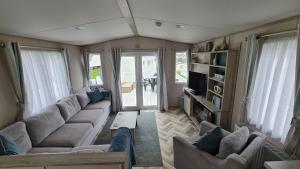 a living room with a couch and a tv at Stunning 2 bed Luxury Caravan at Hoburne Devon Bay, with Hot Tub and sea view in Paignton