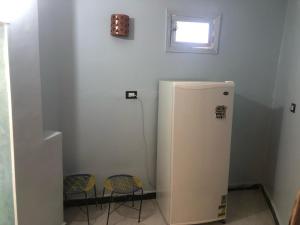 a white refrigerator in a room with two chairs at HAWATY NUBA DWeLL in Nag` el-Ramla
