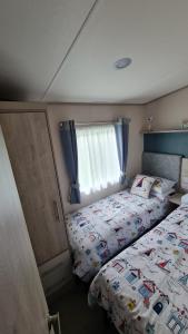 a small bedroom with a bed and a window at Stunning 2 bed Luxury Caravan at Hoburne Devon Bay, with Hot Tub and sea view in Paignton