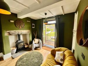 a living room with a couch and a fireplace at Wicket Green Cottage Hayfield in Hayfield