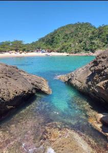 a beach with rocks and a beach with people in the water at Casa de férias em trindade paraty in Paraty +11 photos