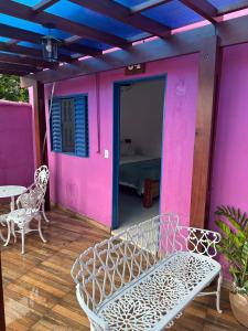 a porch with a white bench and a pink wall at Pousada Refúgio Encantado in Goiás