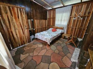 a small room with a bed and a chair in it at Cabaña del Bosque in Tapantí