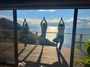 a group of three women doing yoga on a deck at IZU Elysian View in Koura