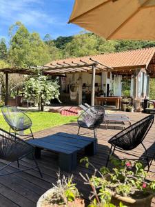 a patio with a table and chairs and an umbrella at Chalé na montanha com vista e lareira Mantiqueira in Costas