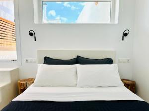 ミコノス・シティにあるSilvernoses Little Venice, Mykonos Townの白いシーツと窓のあるベッドのある寝室