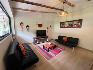 a living room with black leather furniture and a tv at Q'inti Apartment in Lamay +2 photos