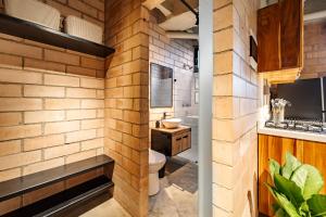 a brick bathroom with a toilet and a sink at Otalu Suites in Medellín