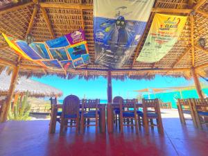 a table and chairs under a straw umbrella on the beach at Palapas Ventana in La Ventana