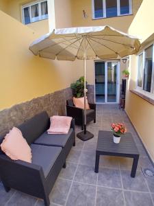 a patio with a couch and an umbrella at Hawaii house in Puerto del Rosario
