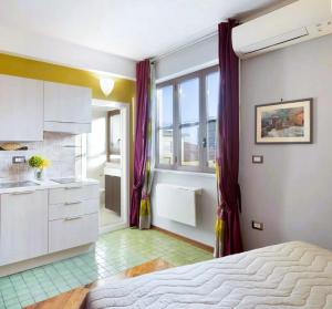 een slaapkamer met een bed en een keuken met paarse gordijnen bij Central Apartment in Salerno