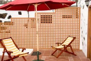 two chairs and a red umbrella on a patio at Casa Rural de 1945 Dos Plantas Patio Y Barbacoa in Frontera