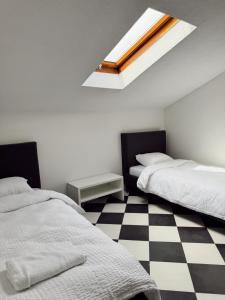 a bedroom with two beds and a checkered floor at Nook 95 Rooms in Prizren