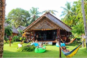 a group of people sitting in hammocks in front of a house at Playgrounds Sabbit Mentawai Surfcamp in Pulau Masokut +23 photos