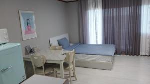 a small bedroom with a bed and a table and chairs at Toursketch Pension in Seogwipo