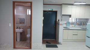 a kitchen with a door open to a bathroom at Toursketch Pension in Seogwipo +14 photos