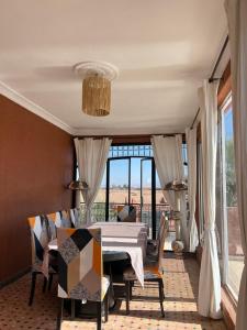 ein Esszimmer mit Tisch und Stühlen und einem großen Fenster in der Unterkunft Exclusive Villa Privée 5 Chambres Route de L Ourika in Aït Bou Zguia