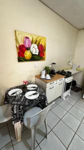 eine Küche mit einem Tisch und einem Tisch und einem Gemälde an der Wand in der Unterkunft Suíte privativa com cozinha completa, ar e Wi-Fi in Palmas