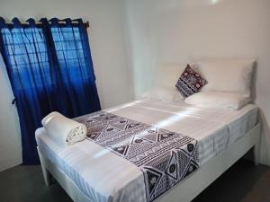 a bedroom with a bed with white sheets and blue curtains at Stephanie's Homestay in Matei
