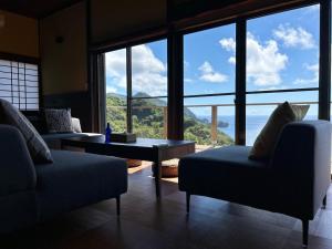 a living room with couches and a view of the ocean at IZU Elysian View in Koura