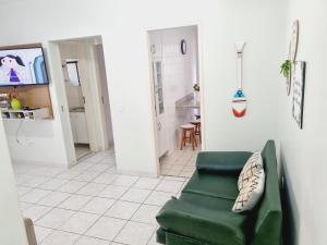 a living room with a green couch and a kitchen at Ed Ravena Com vista mar e elevador in Guarapari