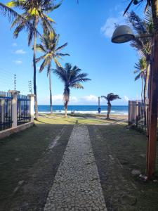 a cobblestone path next to a beach with palm trees at Village Beira mar in Lauro de Freitas