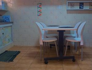 a table with four white chairs in a room at Le house hostel in São Paulo