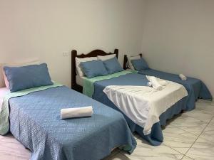 a room with two beds with blue and white sheets at Suítes Sobral in Capitólio