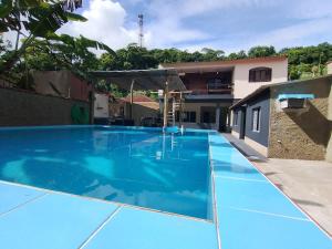 a large blue swimming pool in front of a house at Espaço familiar em Cananeia SP in Cananéia