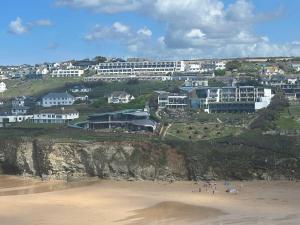 Un grupo de personas en una playa con edificios en un acantilado. en 2 Bed Beach Apartment with Pool!, en Mawgan Porth