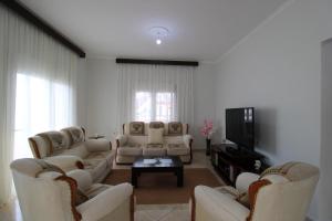 a living room with white furniture and a tv at Vila Eni - Mario in Ksamil