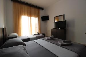 a hotel room with two beds and a television at Vila Eni - Mario in Ksamil