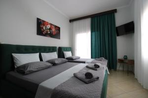 a bedroom with two beds and a green headboard at Vila Eni - Mario in Ksamil