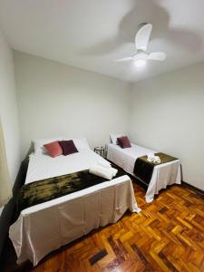 ein Schlafzimmer mit zwei Betten und einem Deckenventilator in der Unterkunft Apto a 5 min da Basílica - 6 pessoas, Garagem, Wi-Fi in Aparecida