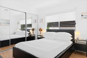 a bedroom with two beds with white sheets and mirrors at Spacious 3-Bed House in Leafy Paddington in Brisbane