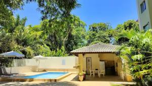 a house with a swimming pool next to a building at Flat Jardim Aeroporto - H in Lauro de Freitas