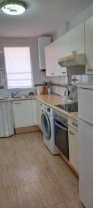 a kitchen with white cabinets and a washer and sink at Casa Karina in Parque Holandes