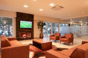 a living room with a fireplace and a tv at Flat 205 Serra Class, piscina, espaço kids, academia, sauna, 5 hóspedes, 4 min Catedral in Canela