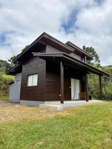 a brown house with a white door in a field at Chalés Bosque das Oliveiras in Urubici
