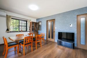 a dining room with a table and chairs and a television at 山響Yufuin Onsen Villa Yamahibiki in Yufu