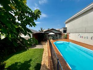 a swimming pool in a yard next to a building at Pousada e Hotel Italian Garden House in Campo Grande
