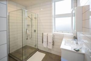 ダニーデンにあるCumberland Street deluxe apartment No4のガラスのシャワーと洗面台を備えたバスルーム